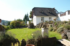 Ferienwohnung Zauberhaft - Außenansicht mit großer Wiese, Blumen und Aufgang zur Terrasse